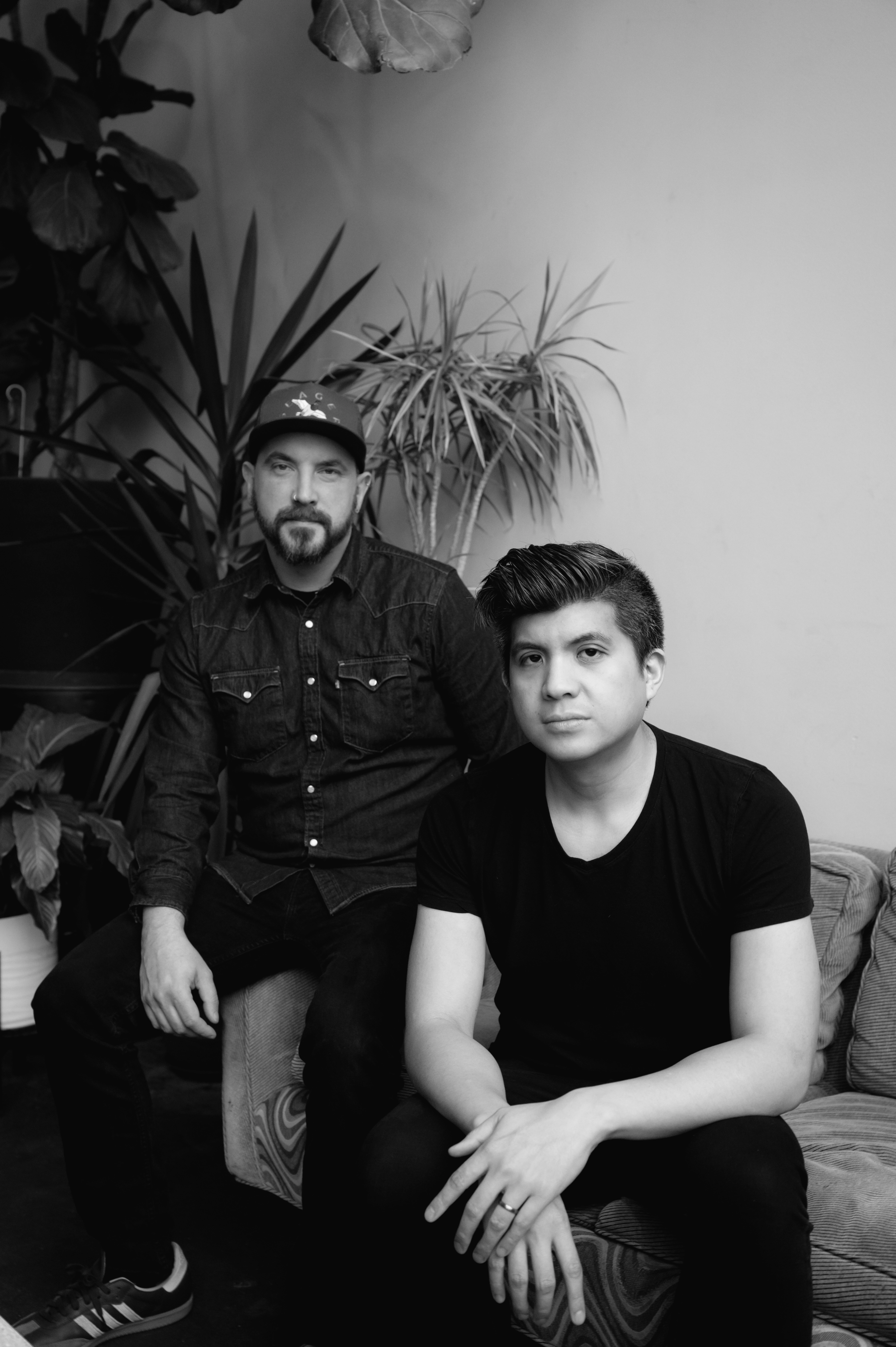 Brian and Joe, sitting on a couch, looking into the camera with serious faces.